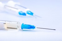 Close-up of plastic syringe on white background. Monochrome tone