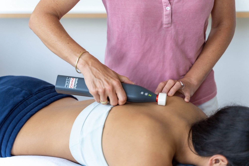 Eine Physiotherapeutin behandelt eine Patientein mit dem Matrixmobil Alpha Synchronizer am Schulterblatt